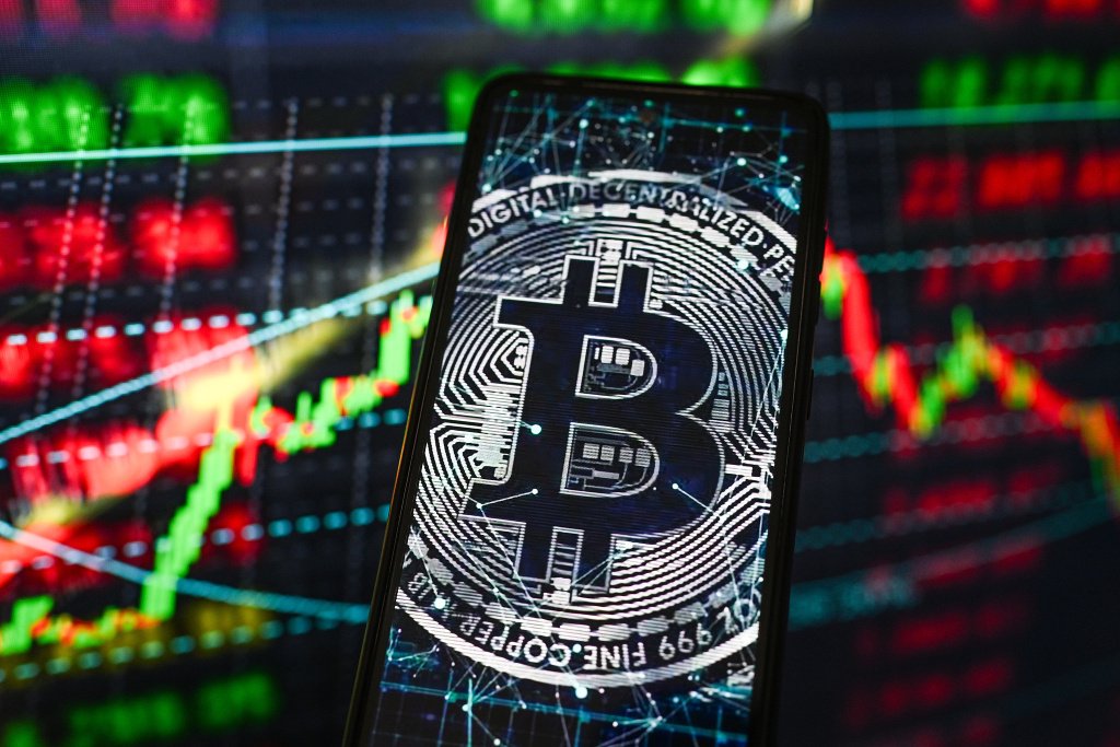 当地时间2026年3月11日，波兰，智能手机屏幕上显示着比特币标志，背景是股市百分比数据。视觉中国 图