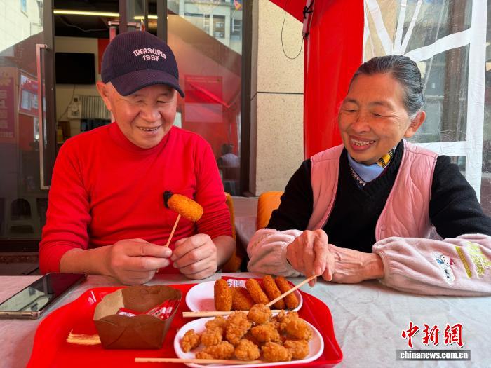 　　3月11日，台胞刘韦麟(左)与妻子吴微微一边品尝自制的台湾小吃一边聊天。中新社记者 岳依桐 摄