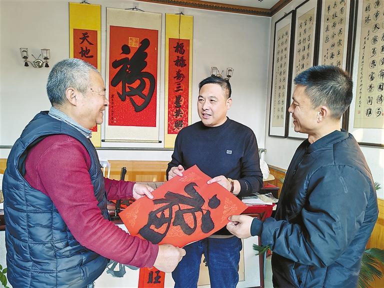 高铁民（左一）给村民送福字。本报记者 杨雅淇 本报通讯员 邓建民 摄