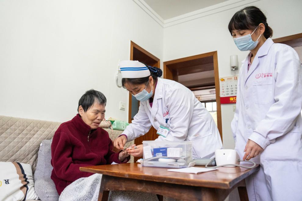 在湖南省长沙市望城区高塘岭街道中南社区，医务人员定期上门为行动不便的居民（左）检查身体。新华社记者 陈思汗 摄