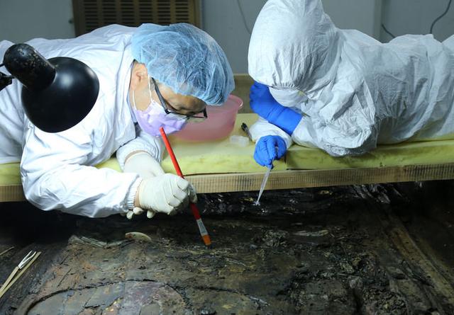 考古工作者在实验室环境下提取海昏侯墓主棺内的文物（资料照片）。新华社发（江西省文物考古研究院供图）
