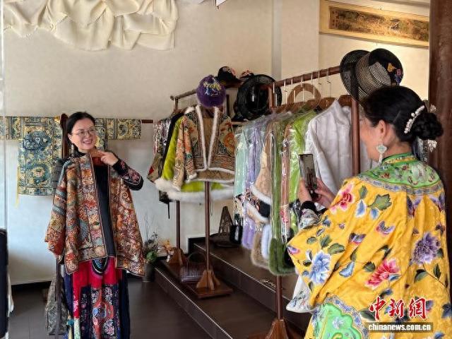 11月15日，贵州凯里，顾客在张理月家的店里挑选苗绣服饰并拍照。 中新社记者 周燕玲 摄