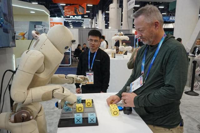 2026年1月8日，在美国拉斯维加斯消费电子展上，一名参观者与傅利叶展区的机器人互动。新华社发（曾慧摄）