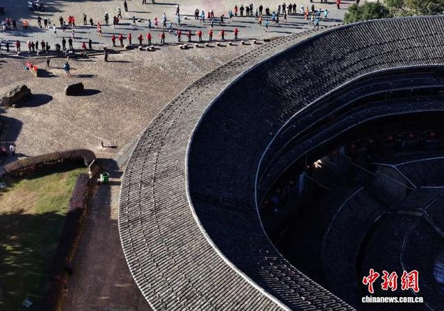 图为参赛选手从土楼旁经过。(无人机照片)中新社记者 张斌 摄