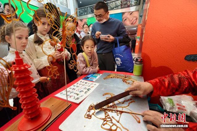 图为中外少年儿童观看天津非物质文化遗产代表性项目糖画制作。中新社记者 佟郁 摄