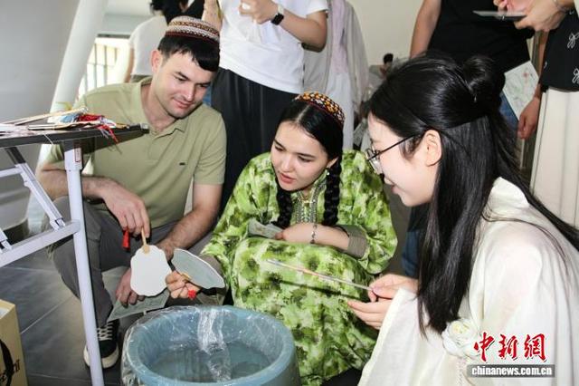 图为中外学子在体验制作漆扇。施轩静 摄