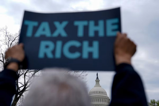 2025 年 4 月 10 日，华盛顿国会山附近一场抗议活动中，示威者举着 “向富人征税” 的标语。