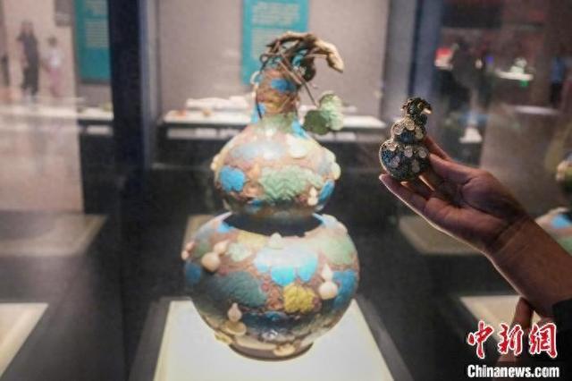 资料图:游客手持“珐琅镶玉葫芦”文创产品与河南博物院馆藏文物对比。 中新社记者 范晓恒 摄