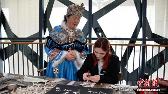 在八岔赫哲族乡八岔村，赫哲族鱼皮制作技艺代表性传承人王海珠教授俄罗斯留学生美丽制作鱼皮“福”字。 于琨 摄