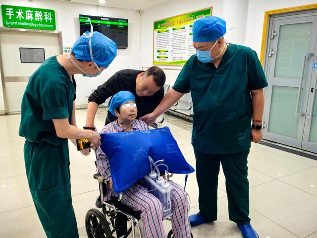 手术后，患者张女士在医护陪同下坐着轮椅回去病房。上海中医药大学附属岳阳中西医结合医院 供图