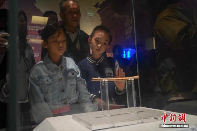 10月1日，国庆中秋假期第一天，位于郑州的河南博物院迎来参观热潮。图为贾湖骨笛吸引小朋友驻足了解。夏青华 摄