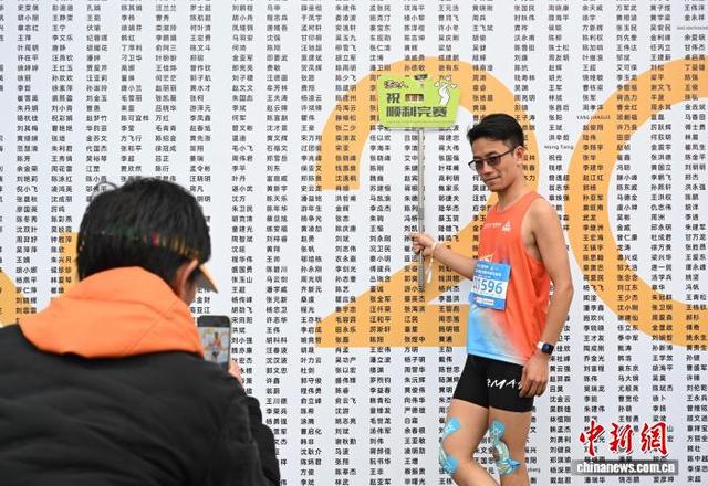 3月22日，参赛者完赛后在姓名墙前拍照。中新社记者 王刚 摄