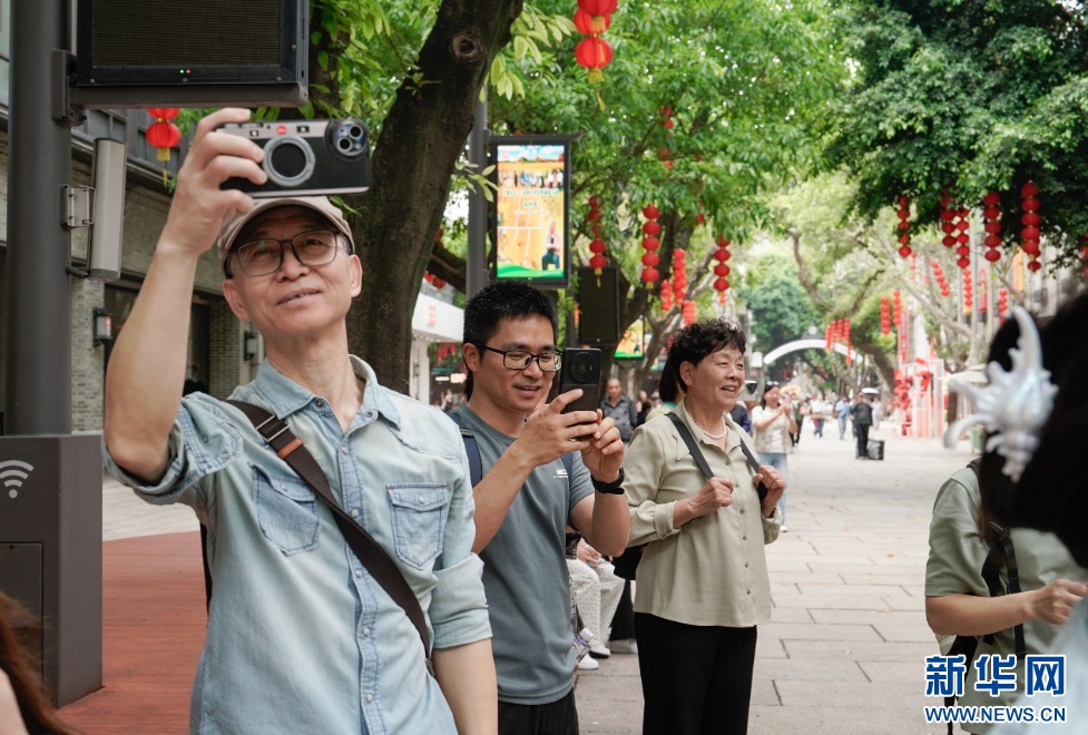   在福州市上下杭历史文化街区，市民游客用手机记录巡游活动。新华网 蒋巧玲 摄