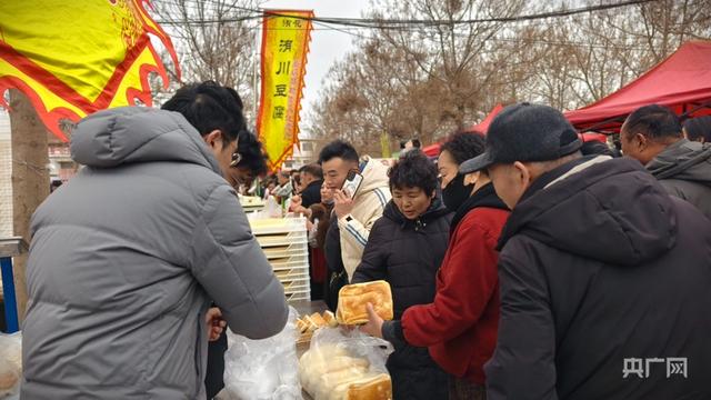 游客在买洧川锅盔、豆腐等美食（央广网记者 郝振青 摄）