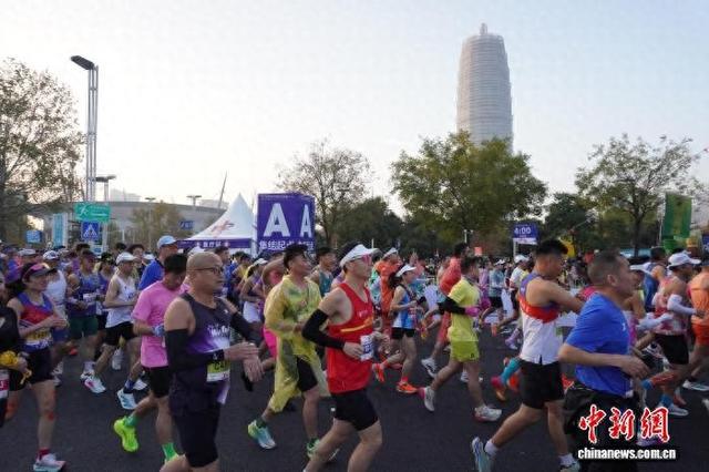 11月16日，河南郑州，2025郑州马拉松参赛选手们跑过郑州城市地标千玺广场。韩章云 摄