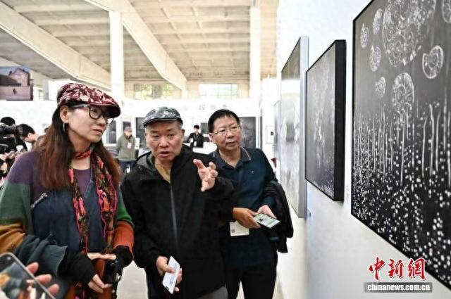 9月19日，第25届平遥国际摄影大展开幕，台湾摄影师林添福(左二)为民众介绍湿版摄影作品。韦亮 摄
