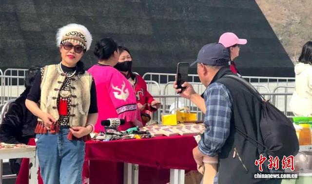 游客试穿赫哲族鱼皮服饰在饶河打卡拍照。 饶河县文化广电和旅游局供图