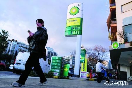 希腊雅典，一名女子拿着手机在路上行走。