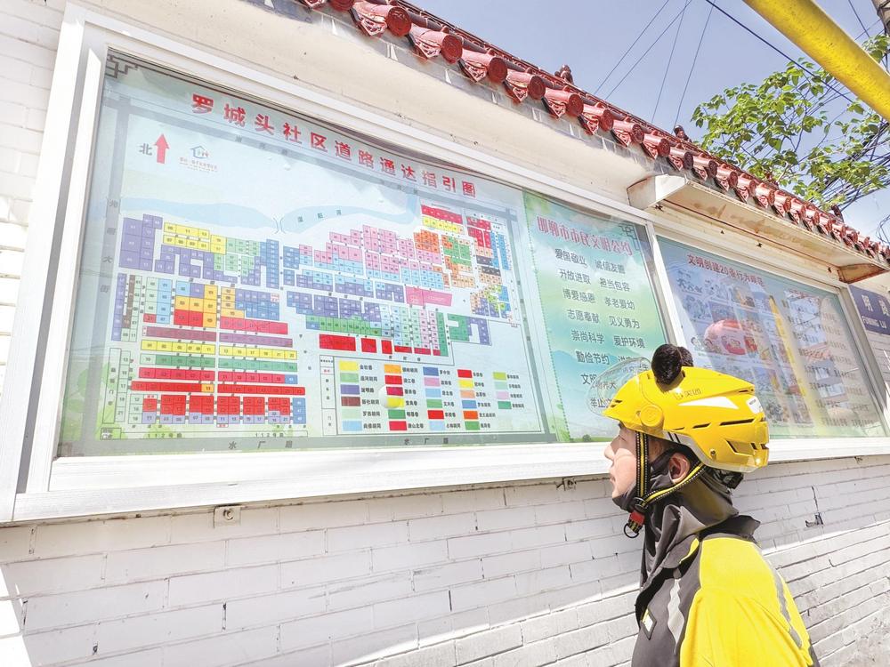 骑手张旭东正在罗城头社区门口查看道路通达指引图。 王丹丹 摄
