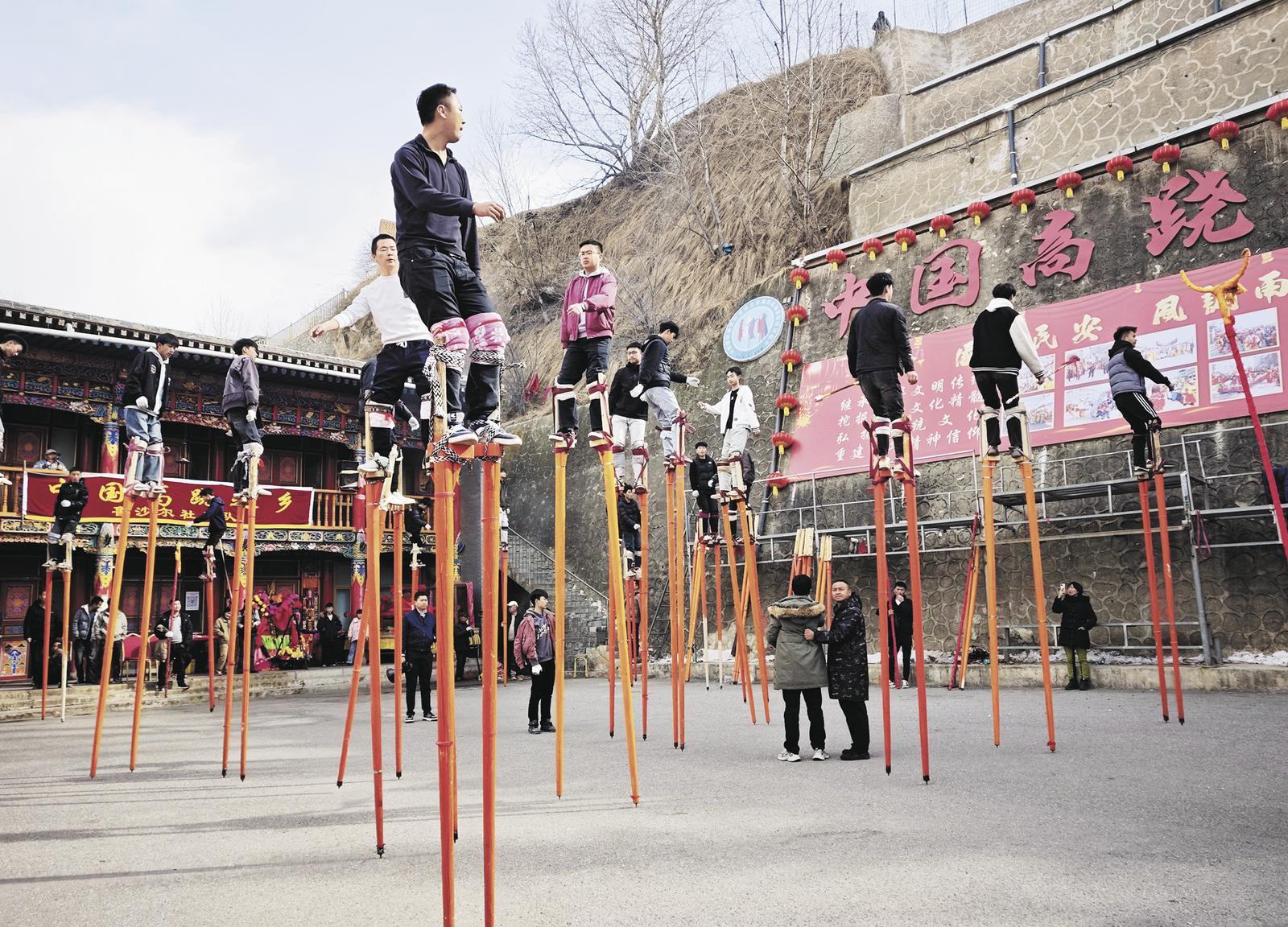 年轻人踩着高跷，和着鼓点练习。本报记者 李庆玲 摄