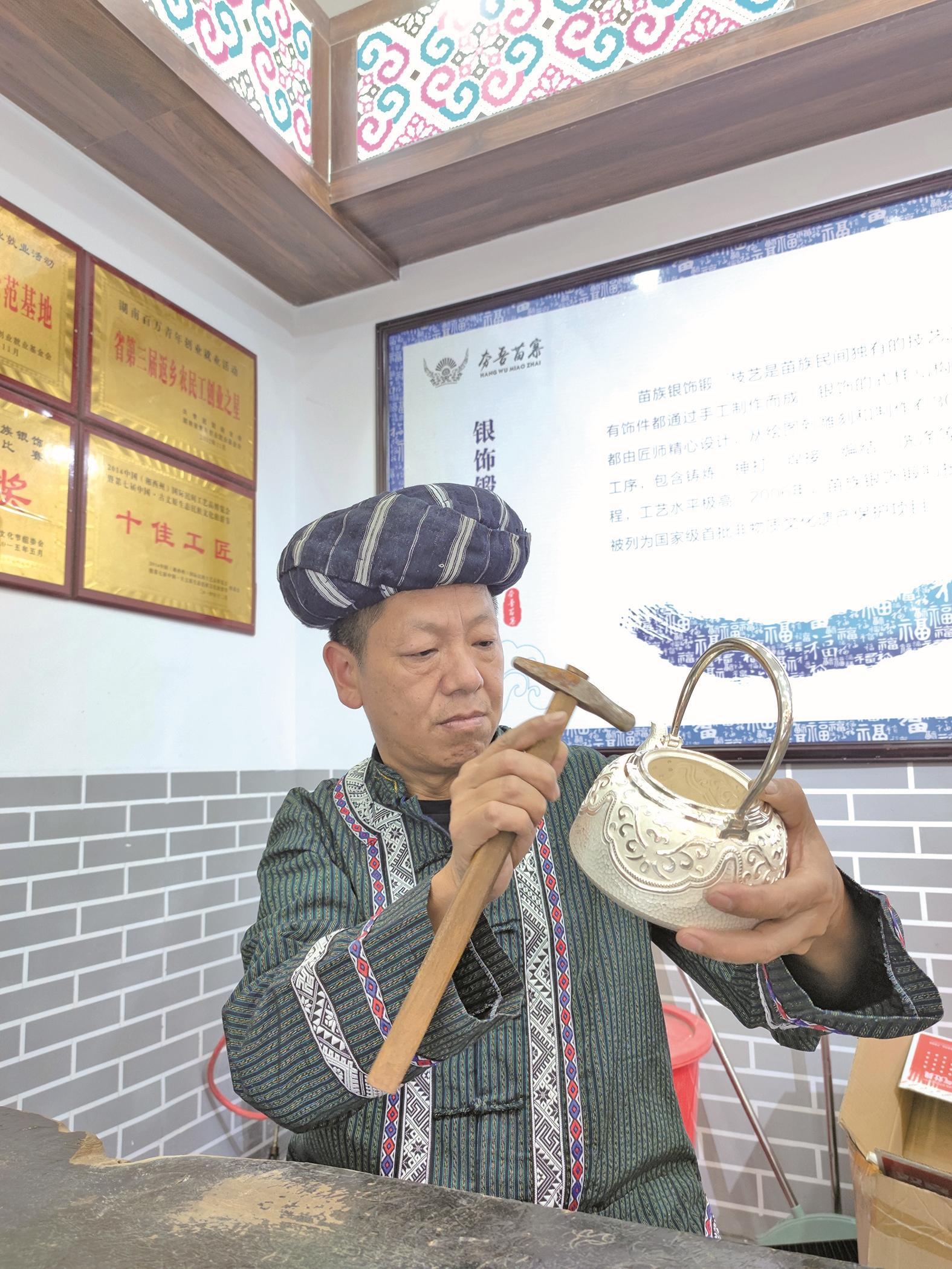　　苗银师傅正在打制银壶 受访者 供图