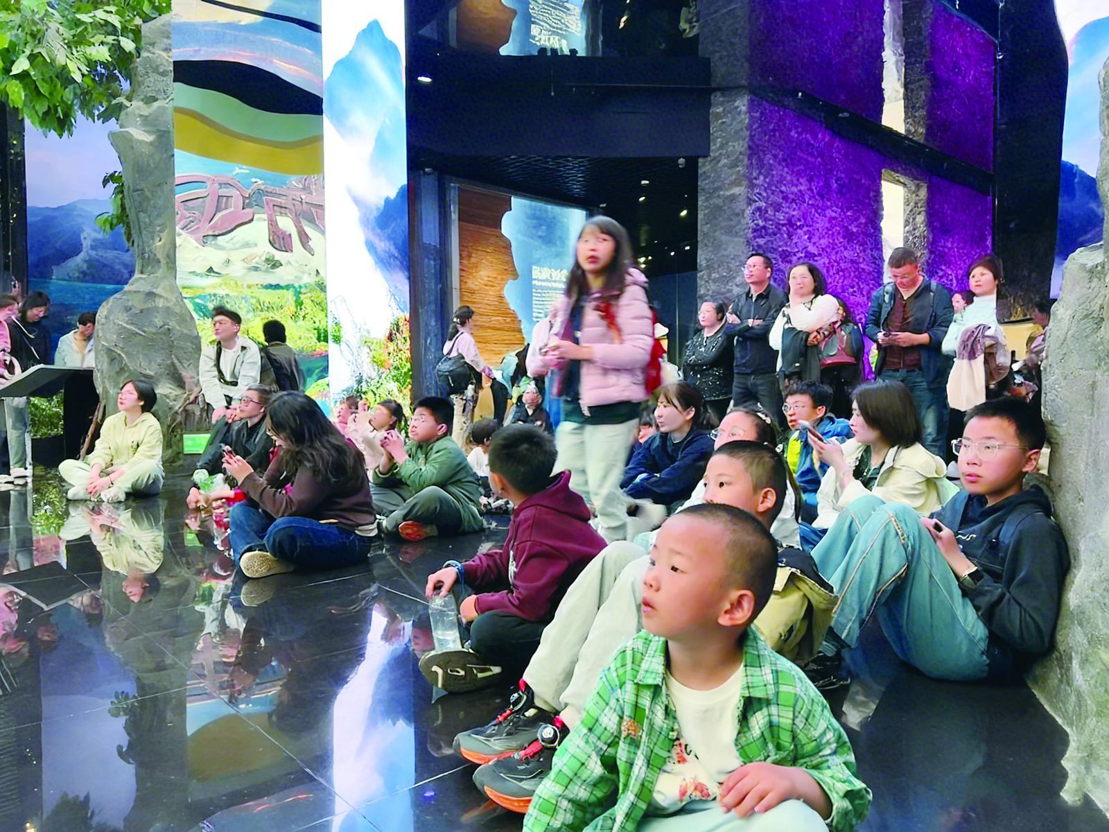 重庆中国三峡博物馆里孩子们席地而坐，观看讲述三峡形成的短片。