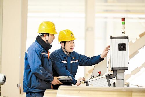 2月4日，张永生（右）为工友讲解轧辊磨床操作注意事项。 本报记者 赵永辉摄