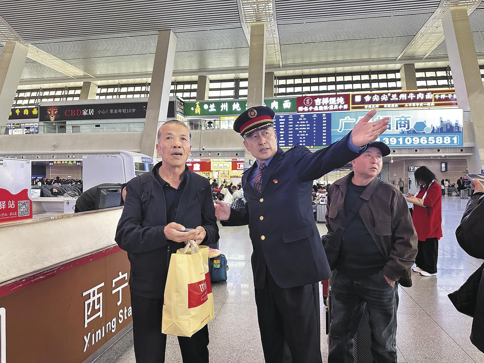 西宁站候车室内，高铭辰正在为老年旅客指引乘车方向。本报记者 王晶 丁玉梅 摄