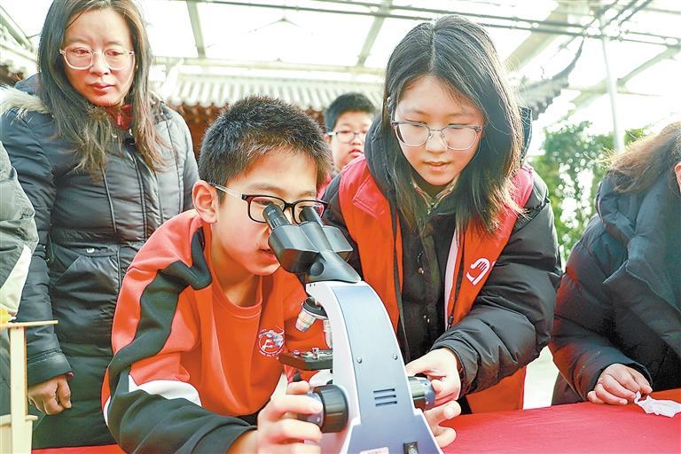 在九天休闲谷，孩子们在志愿者指导下用显微镜观察植物细胞结构。 本报记者 张欢 摄