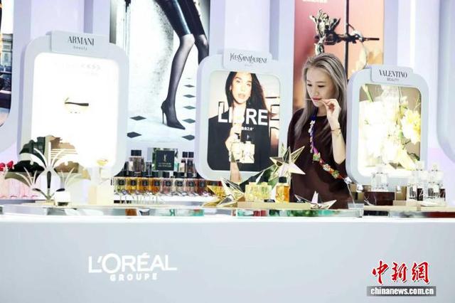 11月5日，第八届进博会上，一位年轻观众在欧莱雅展台前体验最新产品。 中新社记者 汤彦俊摄