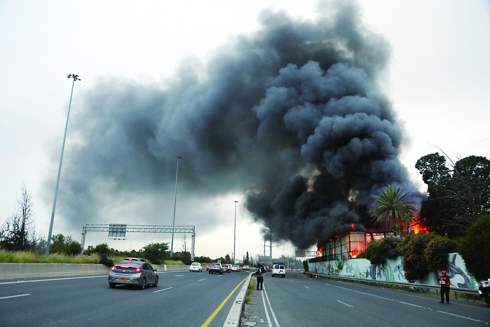 3月13日，在以色列中部城市霍隆，遭伊朗导弹袭击的一处地点冒出滚滚浓烟。
