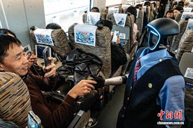 2026年春运期间，机器人乘务员登上高铁，与旅客互动。吴君毅 摄