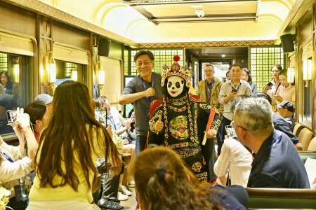 熊猫专列上,旅客与工作人员互动。中国铁路成都局集团有限公司供图