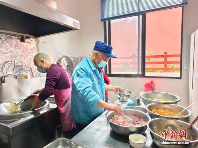 胡赛军(右)与志愿者分工配合，将食堂工作干得有声有色。 陈浩军 摄