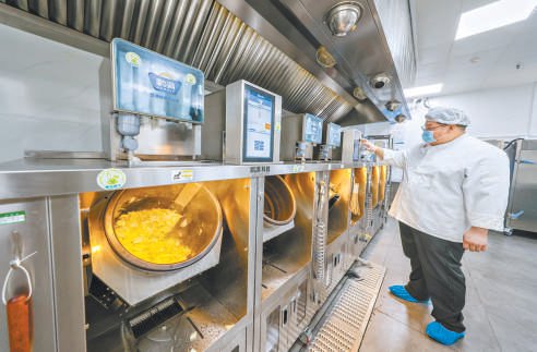 　　平谷中学食堂后厨采用“净菜+炒菜机器人”模式，一人便可操作多台机器。本报记者 潘之望摄