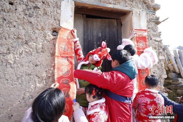 2月8日，浙江嵊州，学子们在泥砖房门前张贴春联。中新社记者 肖健 摄