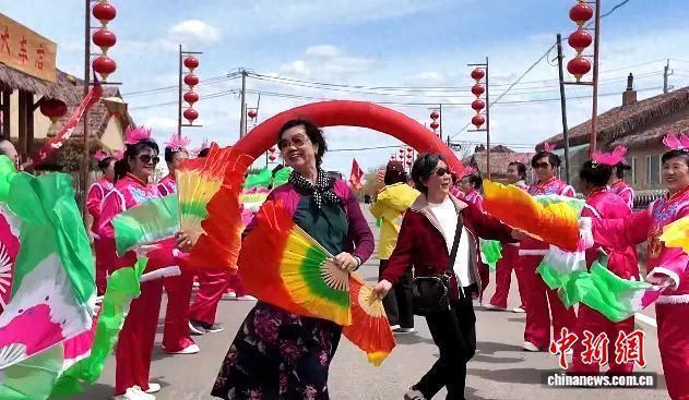 游客在双鸭山市饶河县小南河村与当地民众一起扭秧歌。 饶河县文化广电和旅游局供图