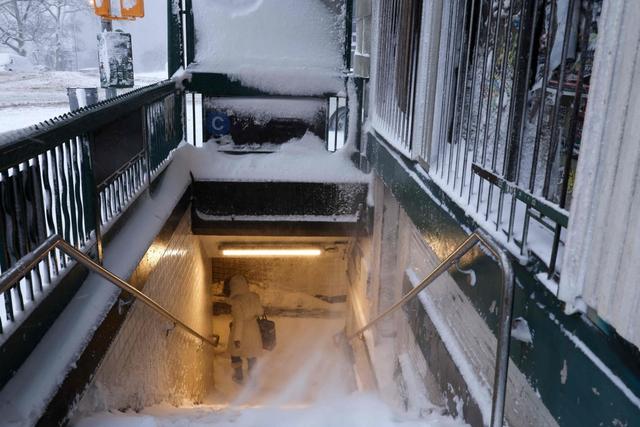 2月23日，美国纽约曼哈顿，一名女子进入积雪的地铁站。视觉中国 图
