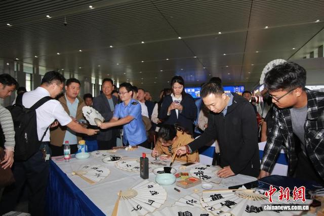图为河南商丘站，铁路书法协会会员书写“文明出行，你我同行”折扇，并赠给参与活动的旅客。王鹏 摄