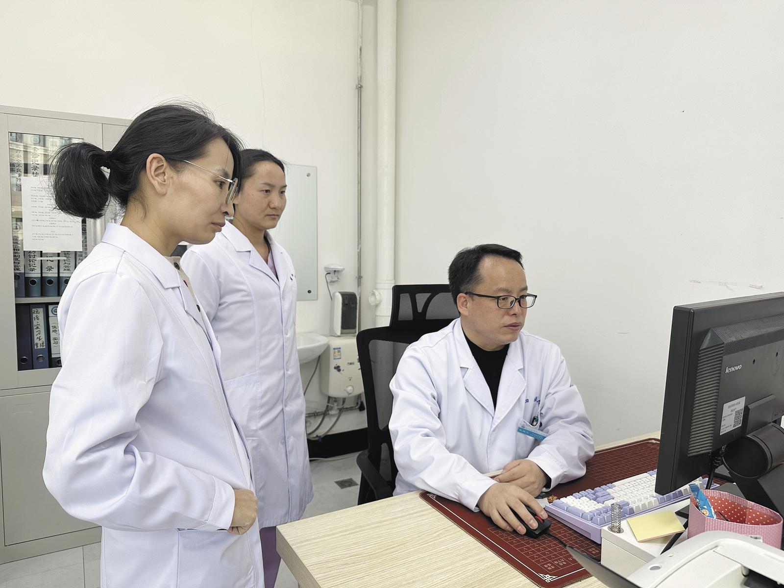 医生赵鹏飞和同事在办公室讨论分析患者病情。本报记者 乔欣 摄
