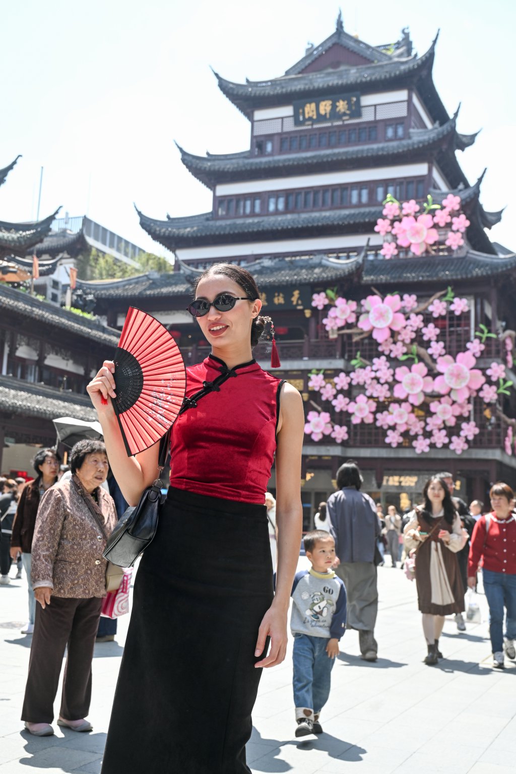 4月18日，上海豫园商城，一名外国游客和天裕楼上的杜鹃花仙子·鹃转春晖装置合影。澎湃新闻记者 朱伟辉 图