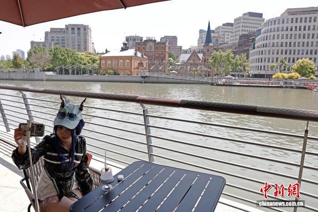 5月1日，游客在上海市虹口区北苏州河路某餐厅外一边品尝美食、一边拍照，享受“五一”假期户外生活。中新社记者 殷立勤 摄