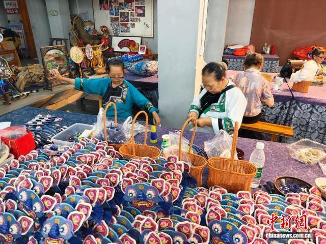 十八洞片区苗绣研学基地内，苗家绣娘正飞针走线，赶制虎头帽、虎头包等热销产品。 张雪盈 摄