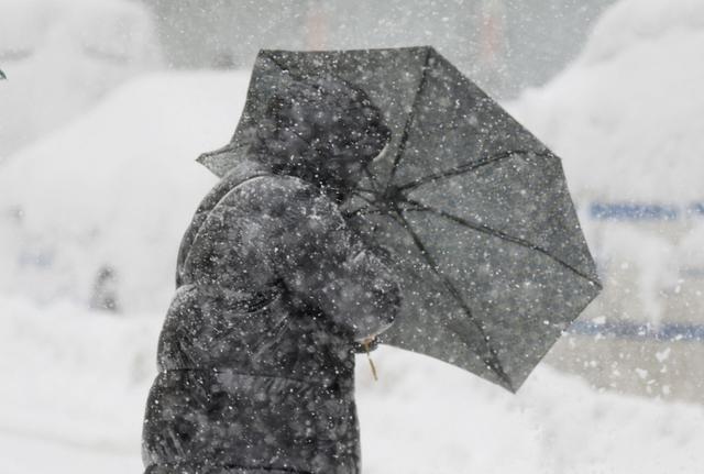 2月23日，美国纽约，一名行人努力固定被强风吹动的雨伞。视觉中国 图