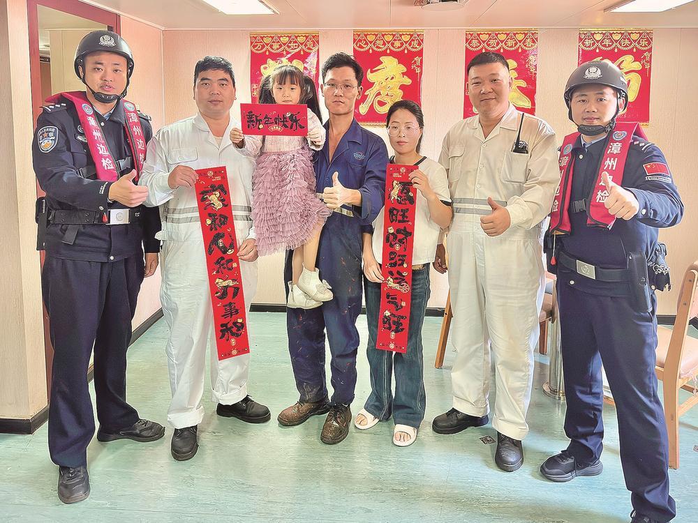 团圆的赵敬威一家三口与边检民警、船员合影。 蓝锦祥 摄