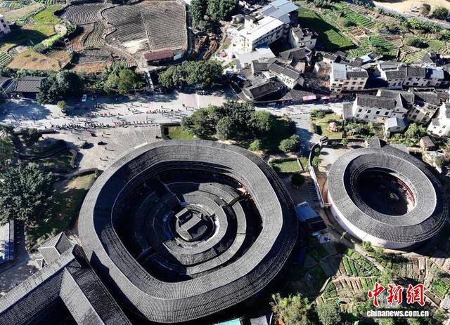 图为参赛选手从高北土楼群旁经过。(无人机照片)中新社记者 张斌 摄