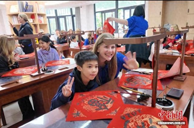 1月11日，美国One Voice儿童合唱团团员与广州青少年体验毛笔书法。(广州市政府外办供图)