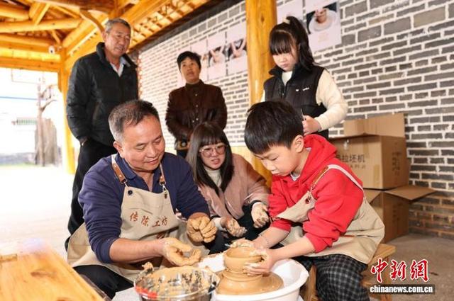 图为在非遗工坊内，传承人正手把手指导游客体验陶瓷制作，沉浸式感受指尖上的非遗魅力。黄尉峰摄