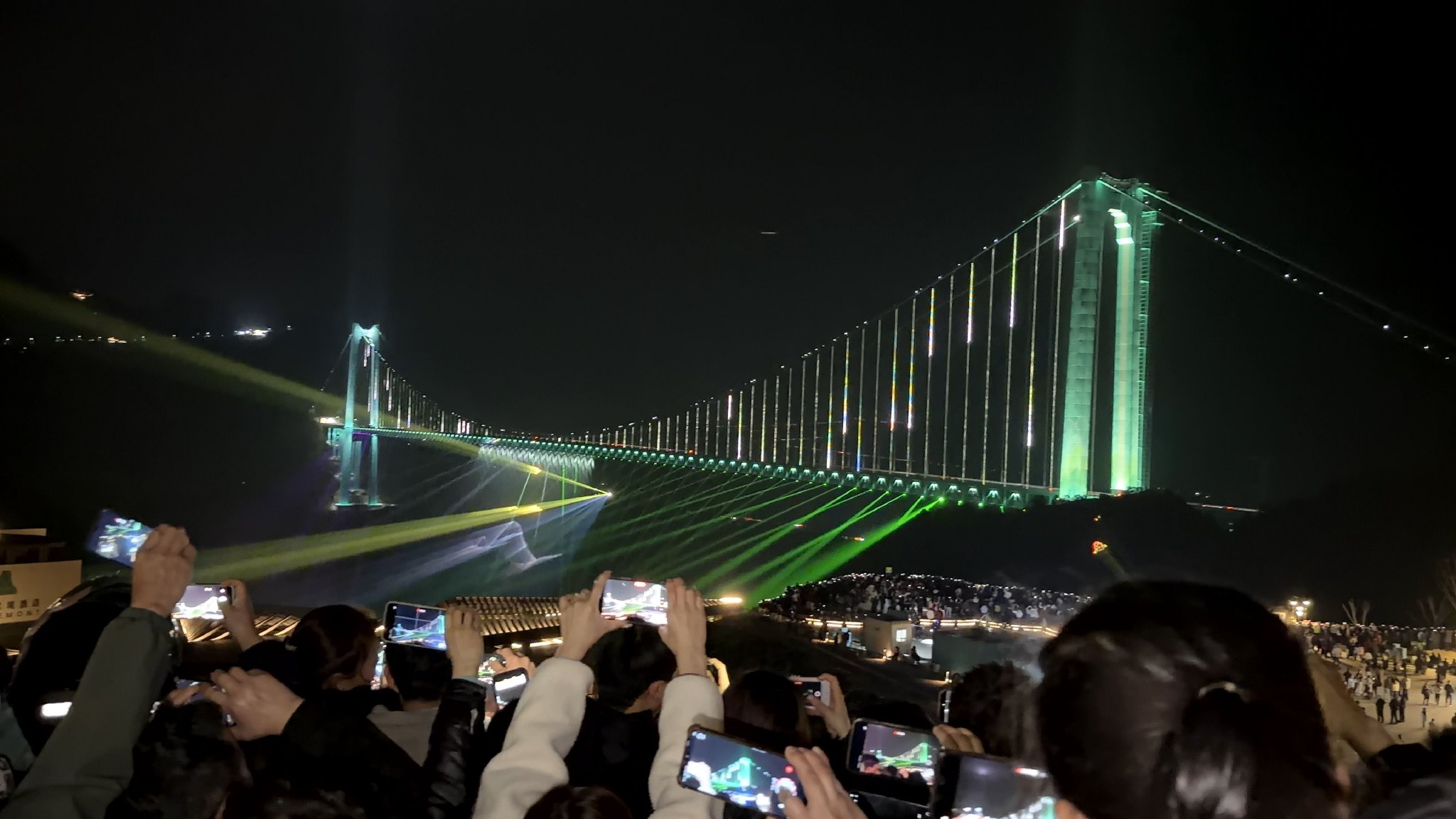 花江峡谷大桥夜景流光，游客纷纷举起手机记录